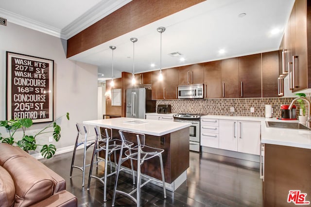 kitchen featuring sink, white cabinetry, stainless steel appliances, pendant lighting, and a breakfast bar area