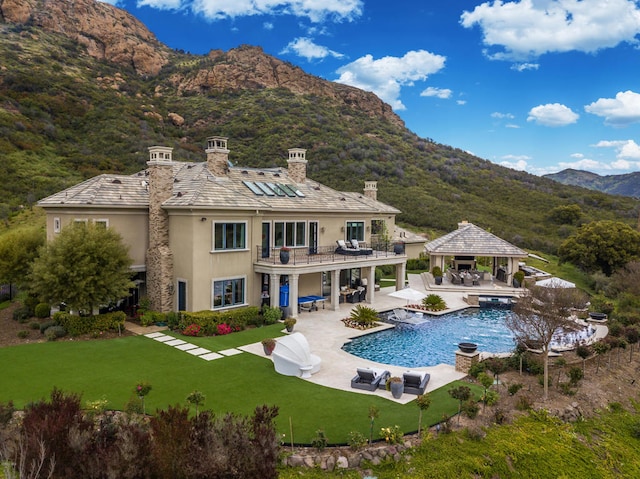 rear view of property with a gazebo, a yard, a mountain view, and a patio