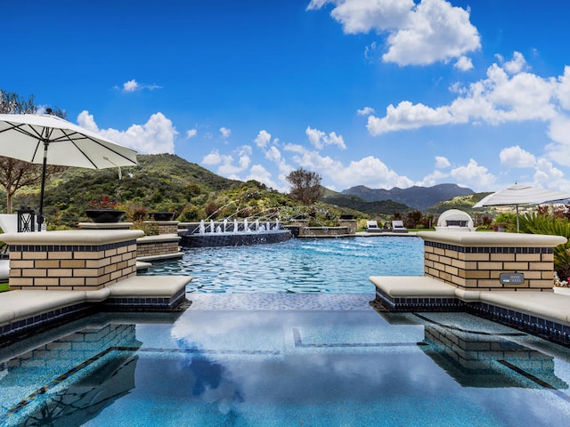 view of pool featuring a hot tub, pool water feature, and a mountain view