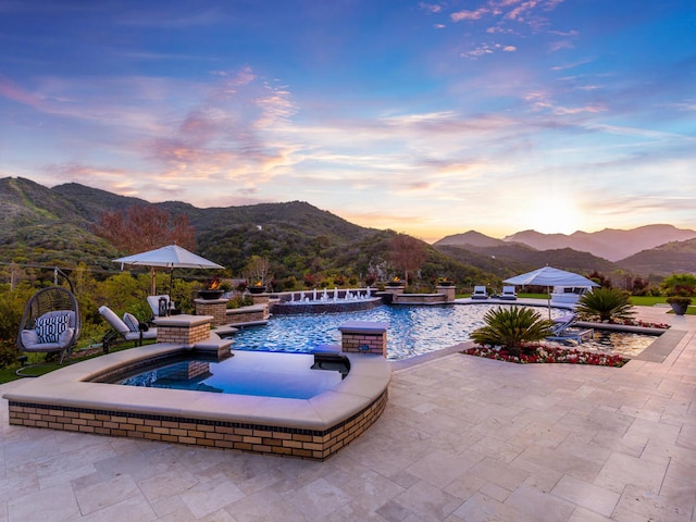 pool at dusk featuring a patio and a mountain view