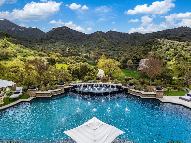 view of swimming pool with a mountain view, pool water feature, and a patio area