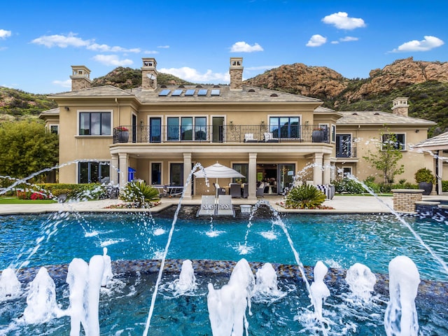 view of swimming pool with pool water feature, a mountain view, and a patio area