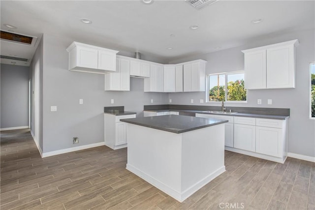 kitchen featuring white cabinets, a kitchen island, sink, and light hardwood / wood-style flooring