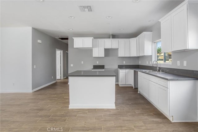 kitchen with white cabinets, a center island, light hardwood / wood-style floors, and sink