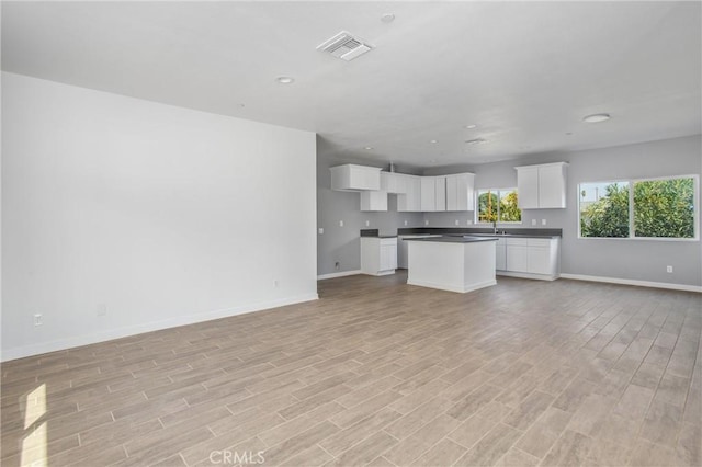 unfurnished living room featuring sink and light wood-type flooring