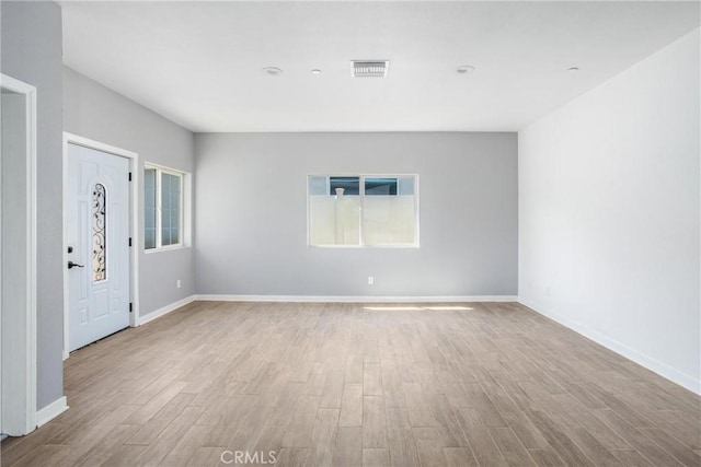 spare room featuring light wood-type flooring and plenty of natural light