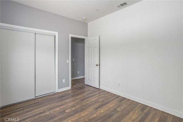 unfurnished bedroom featuring a closet and dark wood-type flooring