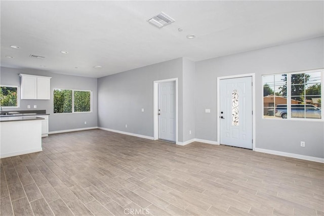 unfurnished living room featuring sink and light hardwood / wood-style flooring