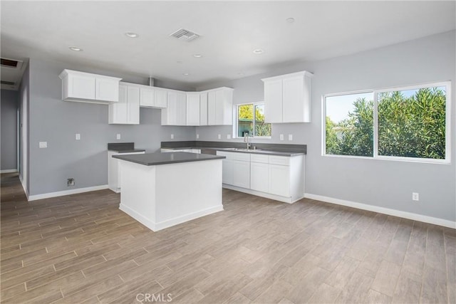 kitchen featuring white cabinets, a center island, sink, and a wealth of natural light