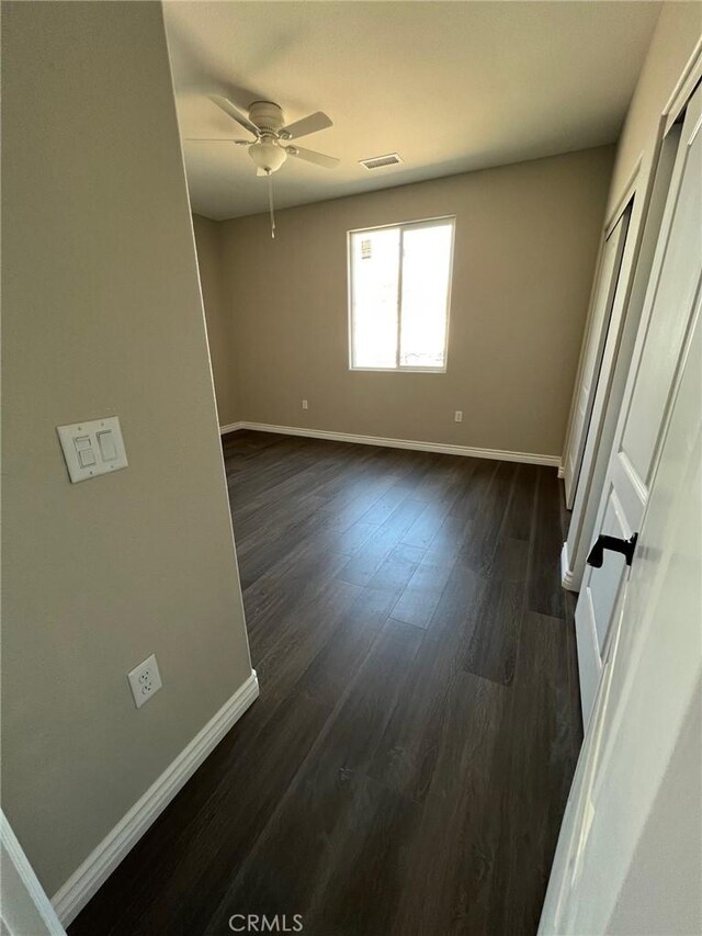 empty room with dark hardwood / wood-style floors and ceiling fan