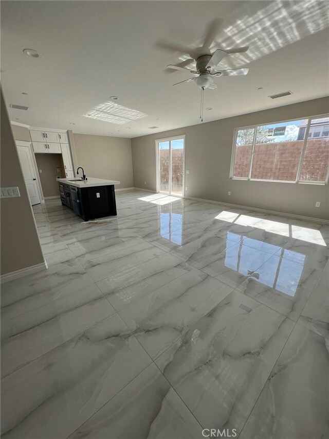 unfurnished room featuring sink, a wealth of natural light, and ceiling fan