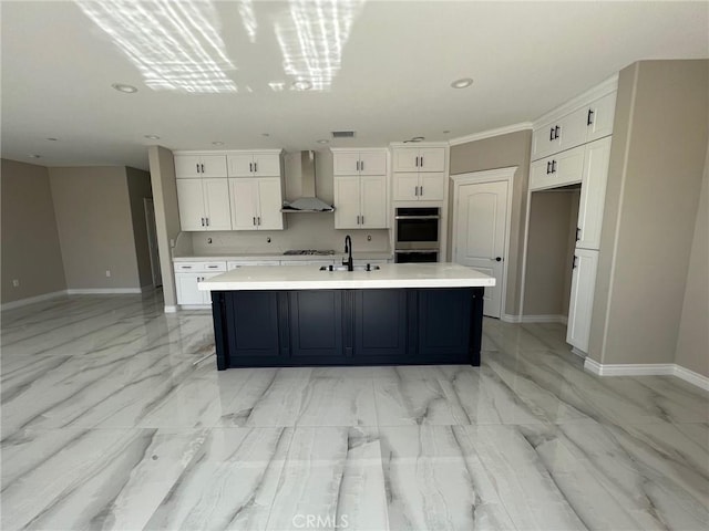 kitchen featuring white cabinetry, an island with sink, gas cooktop, and wall chimney exhaust hood