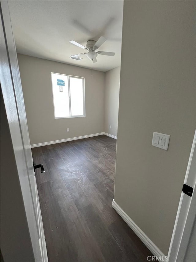 empty room featuring dark wood-type flooring and ceiling fan