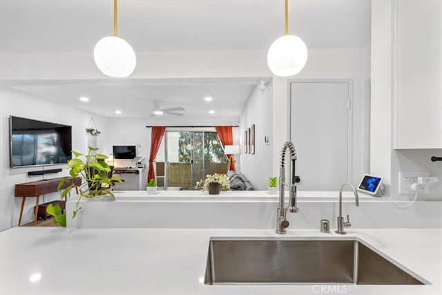 kitchen with white cabinets, sink, ceiling fan, and decorative light fixtures