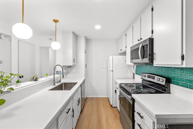 kitchen with white cabinets, appliances with stainless steel finishes, and decorative light fixtures