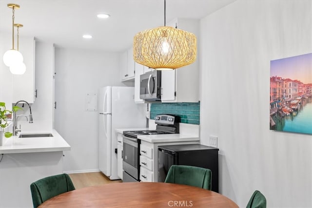 kitchen with hanging light fixtures, sink, stainless steel appliances, and white cabinets