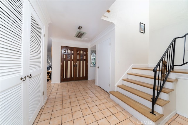 foyer entrance with ornamental molding and light tile patterned floors