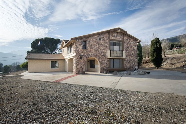 rear view of property with a balcony, a mountain view, and a patio area