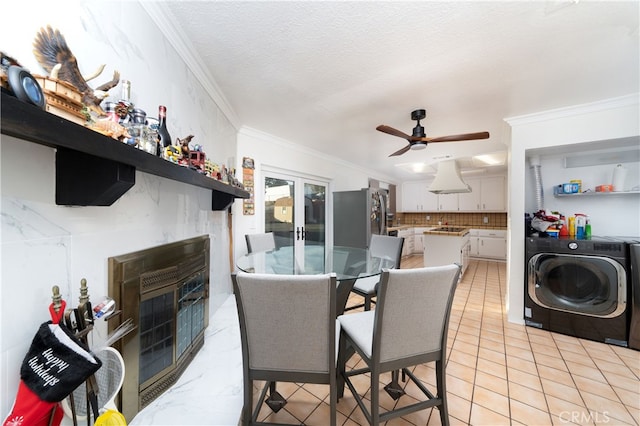 dining area with a textured ceiling, washer and dryer, light tile patterned floors, ornamental molding, and ceiling fan