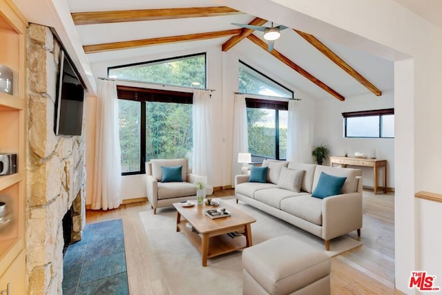 living room featuring ceiling fan, a stone fireplace, high vaulted ceiling, beamed ceiling, and light hardwood / wood-style floors