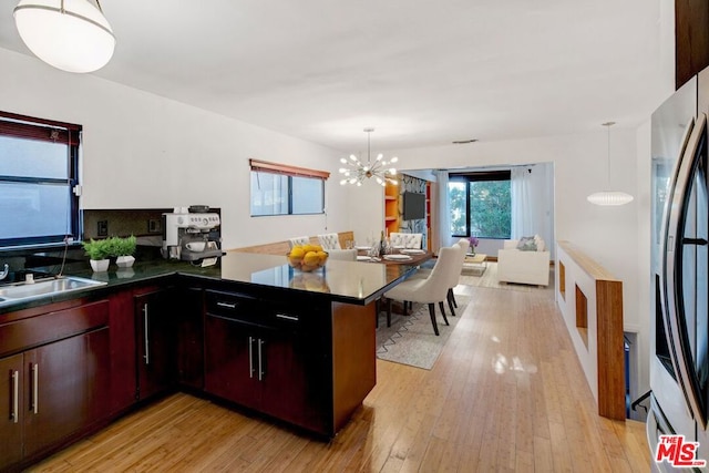 kitchen featuring sink, kitchen peninsula, hanging light fixtures, light hardwood / wood-style floors, and stainless steel refrigerator with ice dispenser