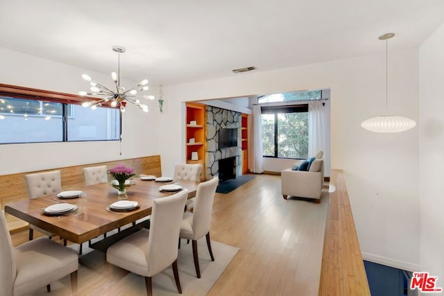 dining area with a chandelier, a fireplace, and light hardwood / wood-style floors