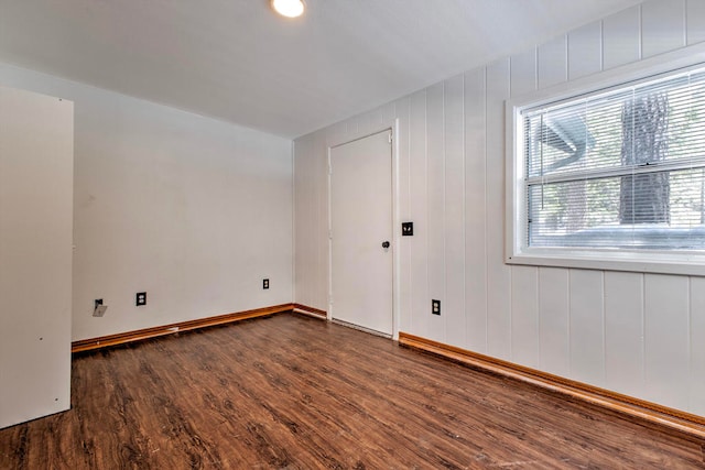 empty room with wooden walls and dark hardwood / wood-style floors