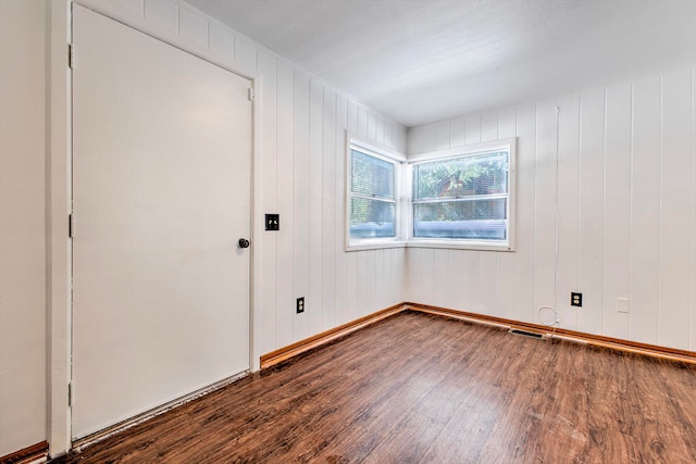 spare room with wooden walls and dark hardwood / wood-style flooring