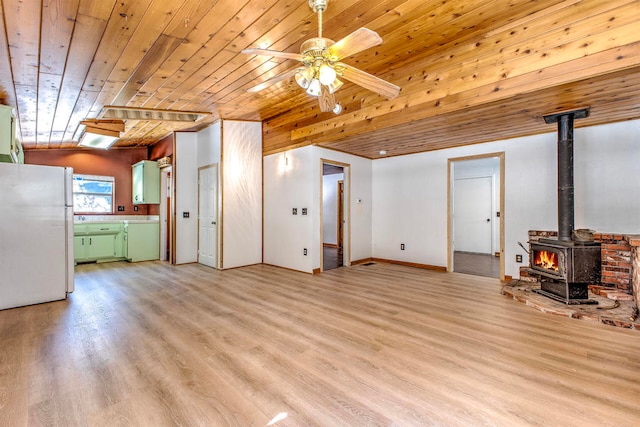 unfurnished living room with light hardwood / wood-style floors, wood ceiling, ceiling fan, and a wood stove