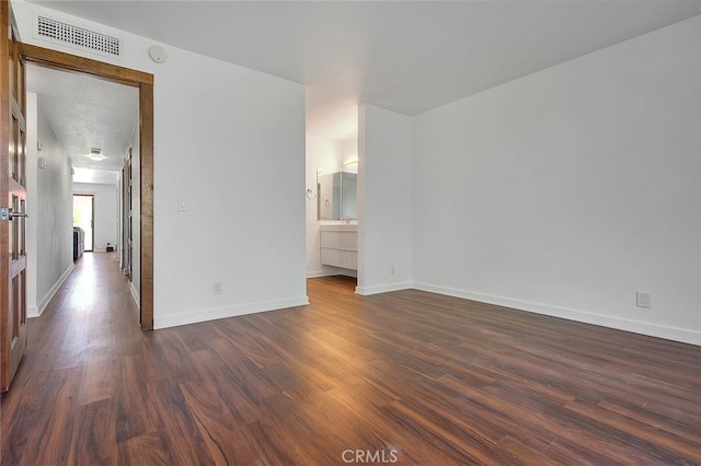 spare room featuring a textured ceiling and dark hardwood / wood-style flooring