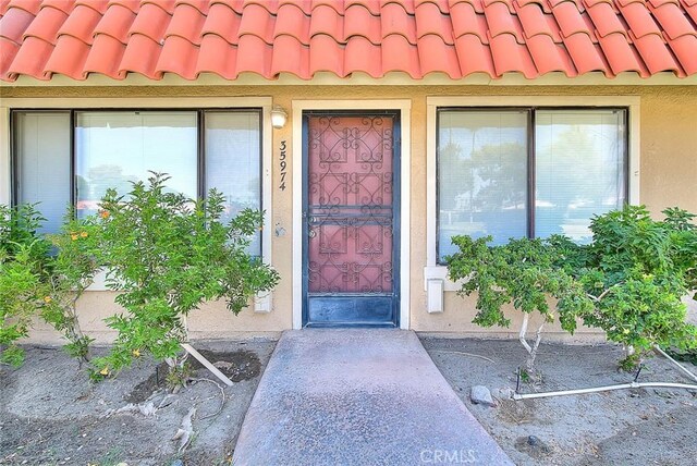 property entrance featuring stucco siding and a tiled roof