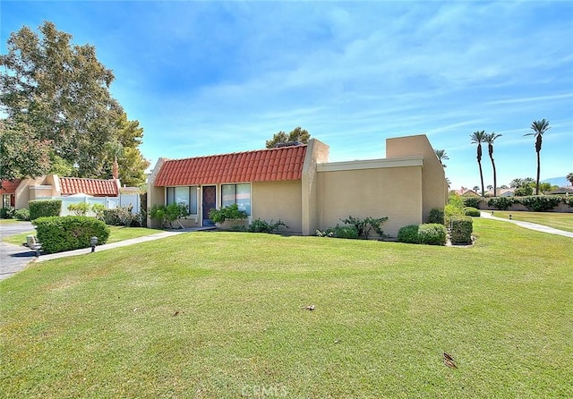 view of front of home with a front lawn, stucco siding, and a tile roof