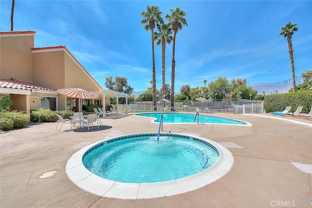 view of pool featuring a hot tub, a mountain view, and a patio area