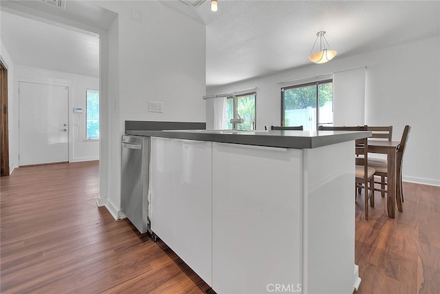 kitchen featuring white cabinets, pendant lighting, kitchen peninsula, a textured ceiling, and dark wood-type flooring