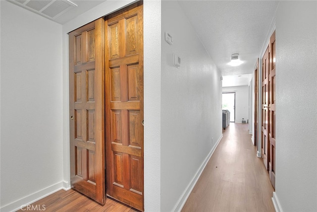 hall with light hardwood / wood-style floors and a textured ceiling