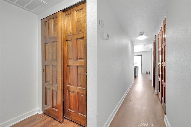hallway featuring visible vents, baseboards, and light wood-style floors
