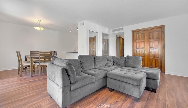 living area featuring visible vents, wood finished floors, and baseboards