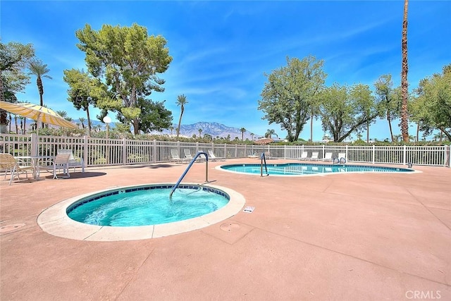 view of swimming pool featuring a mountain view, a hot tub, a patio area, and fence