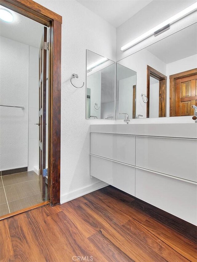 bathroom with baseboards, wood finished floors, and vanity