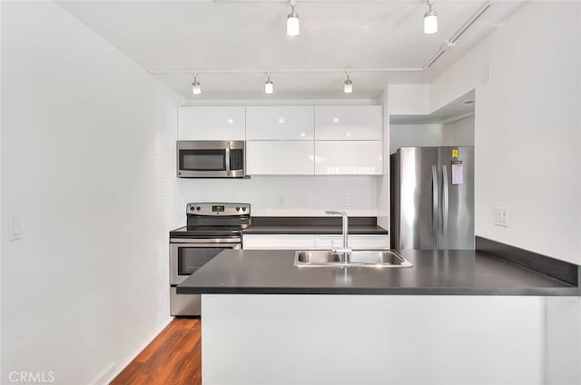 kitchen with track lighting, sink, white cabinetry, kitchen peninsula, and appliances with stainless steel finishes