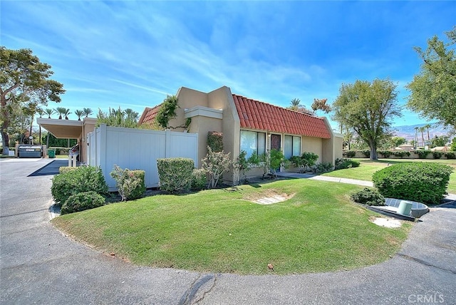 view of front of home with fence, stucco siding, a front lawn, and a tile roof