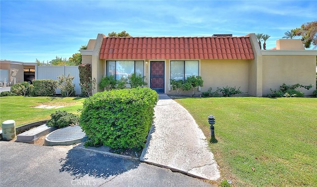 view of front of home featuring stucco siding, a tiled roof, and a front yard