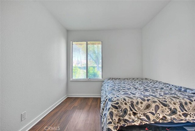 bedroom with dark wood-style floors and baseboards