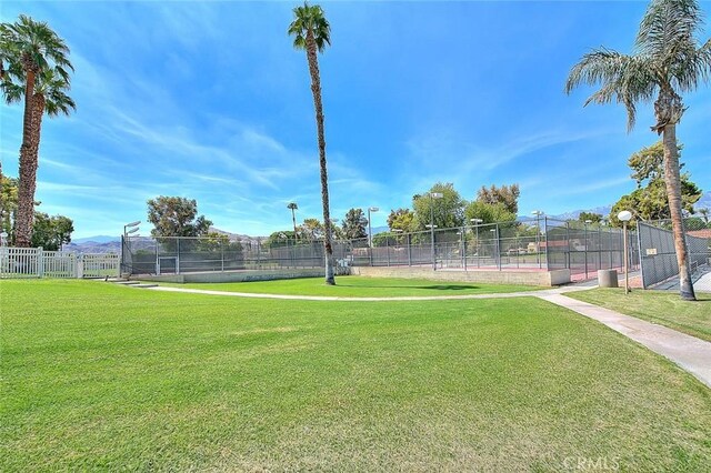 view of home's community featuring fence, a yard, and a tennis court