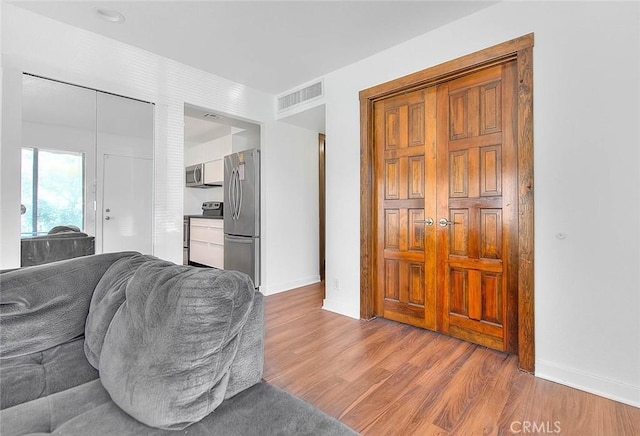 living area with visible vents, wood finished floors, and baseboards