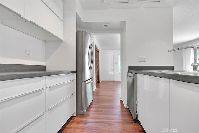 kitchen featuring a sink, visible vents, white cabinetry, dark countertops, and appliances with stainless steel finishes