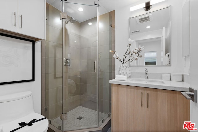 bathroom with vanity, toilet, and a shower with shower door