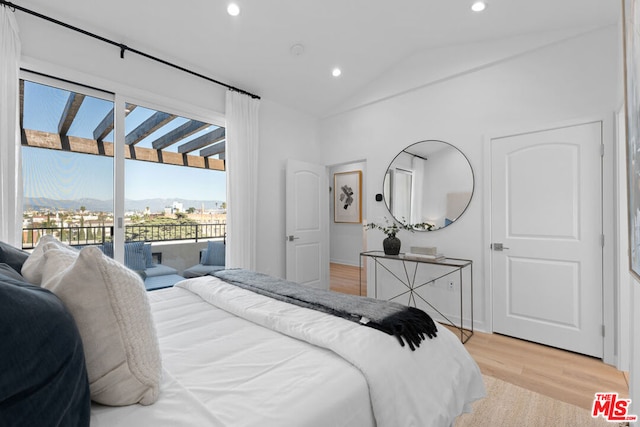 bedroom featuring a mountain view, lofted ceiling, light wood-type flooring, and access to exterior