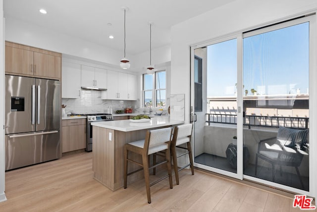 kitchen featuring a breakfast bar, white cabinets, kitchen peninsula, light hardwood / wood-style flooring, and appliances with stainless steel finishes