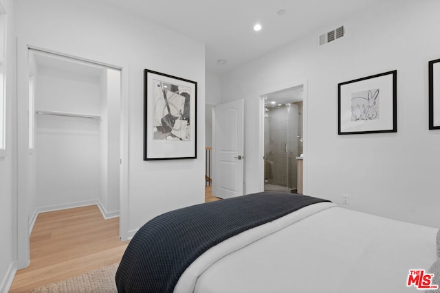 bedroom featuring light hardwood / wood-style flooring, a closet, a walk in closet, and ensuite bathroom